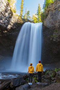 Rear view of man standing against waterfall