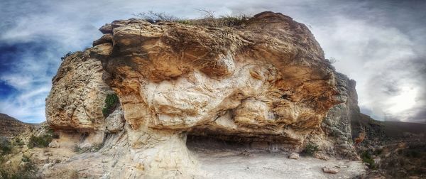 Rock formation on landscape against sky