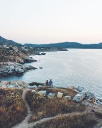 Rear view of people looking at sea against clear sky