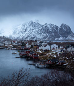 Houses by snowcapped mountains against sky during winter