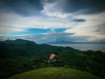 Man jumping over land against sky