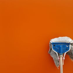 Close-up of mop against orange wall