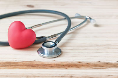 Close-up of stethoscope with heart shape on wooden table