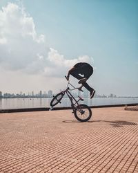 Man bmx cycling on promenade in city against blue sky