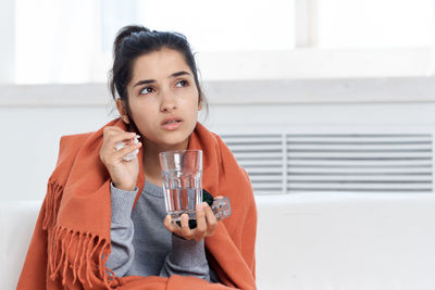 Portrait of young woman sitting on sofa at home