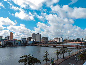 Buildings by river against sky in city