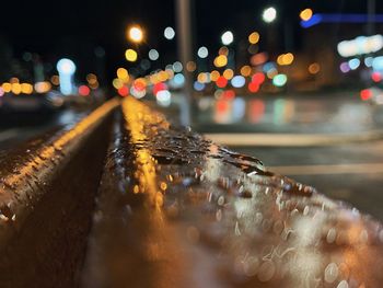 Close-up of wet illuminated city street during rainy season