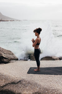 Side view of young woman standing at beach