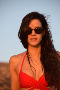 Portrait of smiling young woman wearing sunglasses against sky