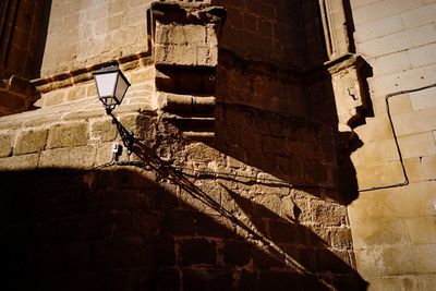 Low angle view of bird perching on brick wall