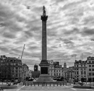 Statue in city against cloudy sky