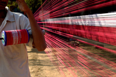 Man holding spool while standing by thread at field