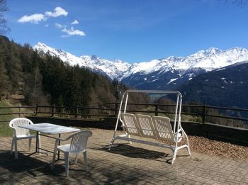 Empty chairs on snow covered mountain against sky