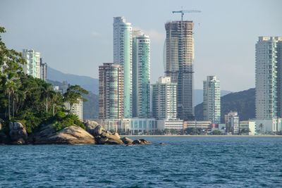 Sea by buildings against sky in city