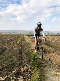 Full length of woman riding bicycle on field