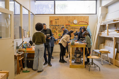 Customers and workers in electronic repair workshop at recycling center