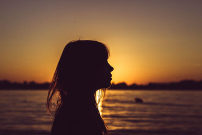 Side view of silhouette woman at beach against sky during sunset