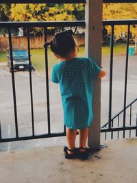 Rear view of boy standing by railing