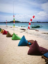 Deck chairs on beach against sky