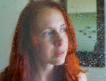 Portrait of woman with raindrops on window
