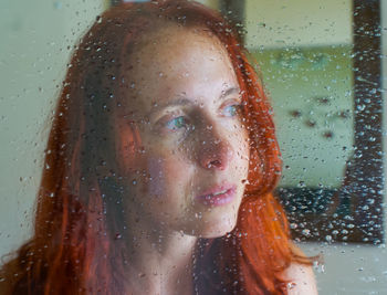 Portrait of woman with raindrops on window