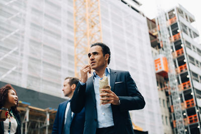 Low angle view of man looking at city buildings