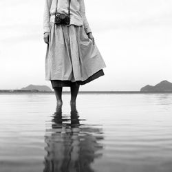 Low section of woman standing at beach