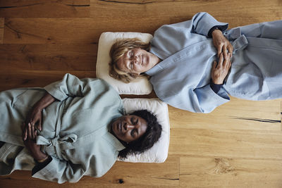 Multiracial female friends wearing bathrobes while relaxing together on floor at home