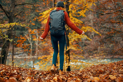 Rear view of man standing on leaves during autumn