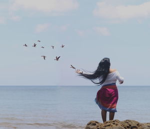 Rear view of young woman standing on beach