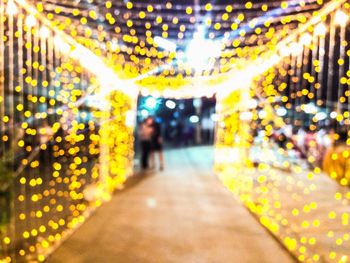 Defocused image of people walking in illuminated lights at night