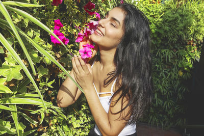 Beautiful woman by flowering plant outdoors