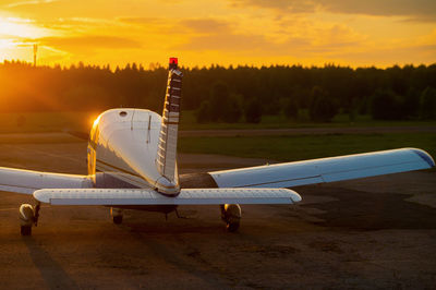 Airplane on airport runway against sky during sunset