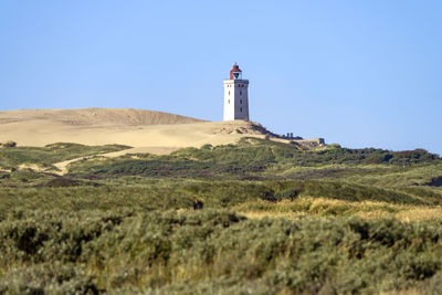 Lighthouse on landscape against clear sky