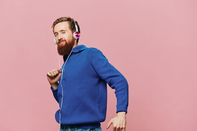 Young man standing against pink background