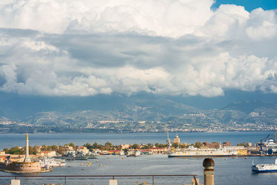 City at waterfront against cloudy sky