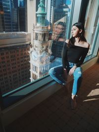 Thoughtful woman sitting on window sill