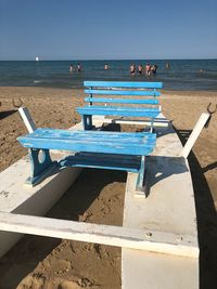 Deck chairs on beach against sky