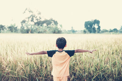 Rear view of boy standing on field