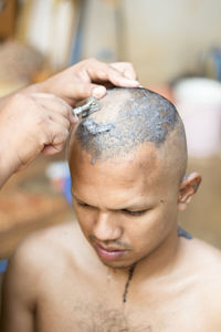 Cropped hands of barber shaving man head