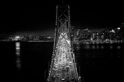 Illuminated bridge over river in city at night