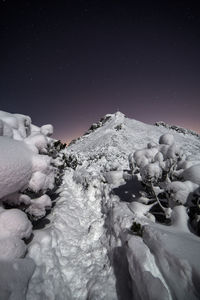 Scenic view of snow covered land against clear sky at night