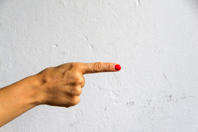 Close-up of hand against white wall