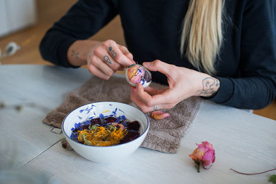 Midsection of woman making easter egg with petals