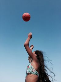 Low angle view of young woman playing clear sky