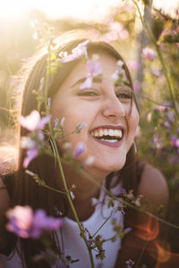 Teenager looking at the camera and laughing among flowers in nature