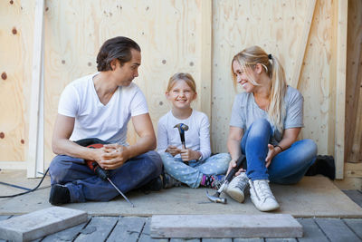 Family sitting on porch of house being renovated