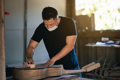 Man working over guitar on table