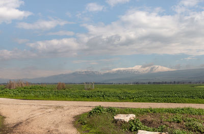 View of field against cloudy sky