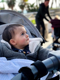 Little boy in his baby carriage, looking around, serious on a winter day. with a blanket on her lap.